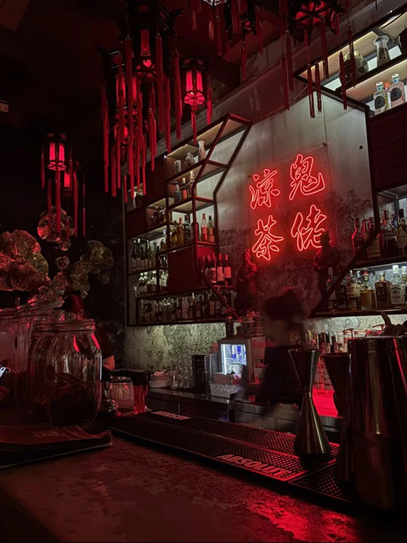A bar glowing red with neon script